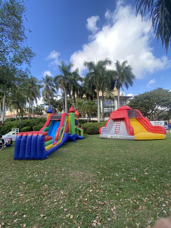 Crazy Games FL bounce house combo and inflatable slide set up in a park with palm trees in Palm Beach County