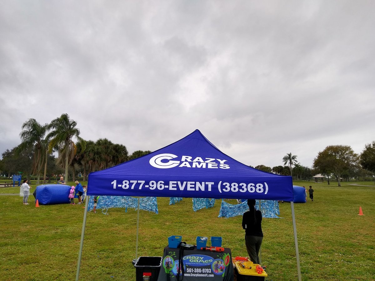 Blue Crazy Games tent set up on a park lawn in Palm Beach County for a fall festival