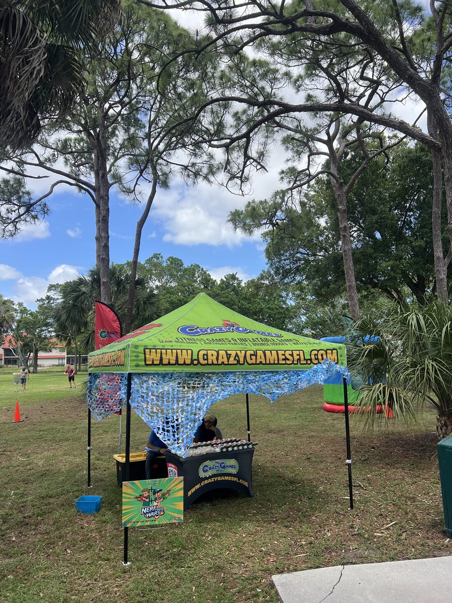 Green Crazy Games FL 10 by 10 tent with a game table at a park event in Palm Beach County