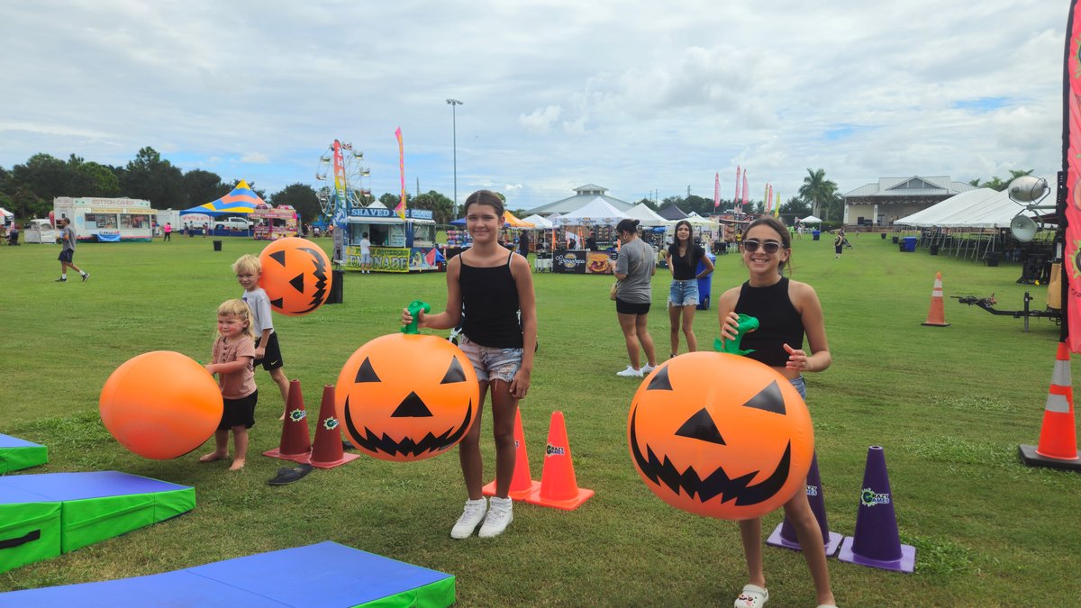 Kids and teens playing with inflatable jack-o-lantern balls, cones and mats at an outdoor fall festival run by Crazy Games FL