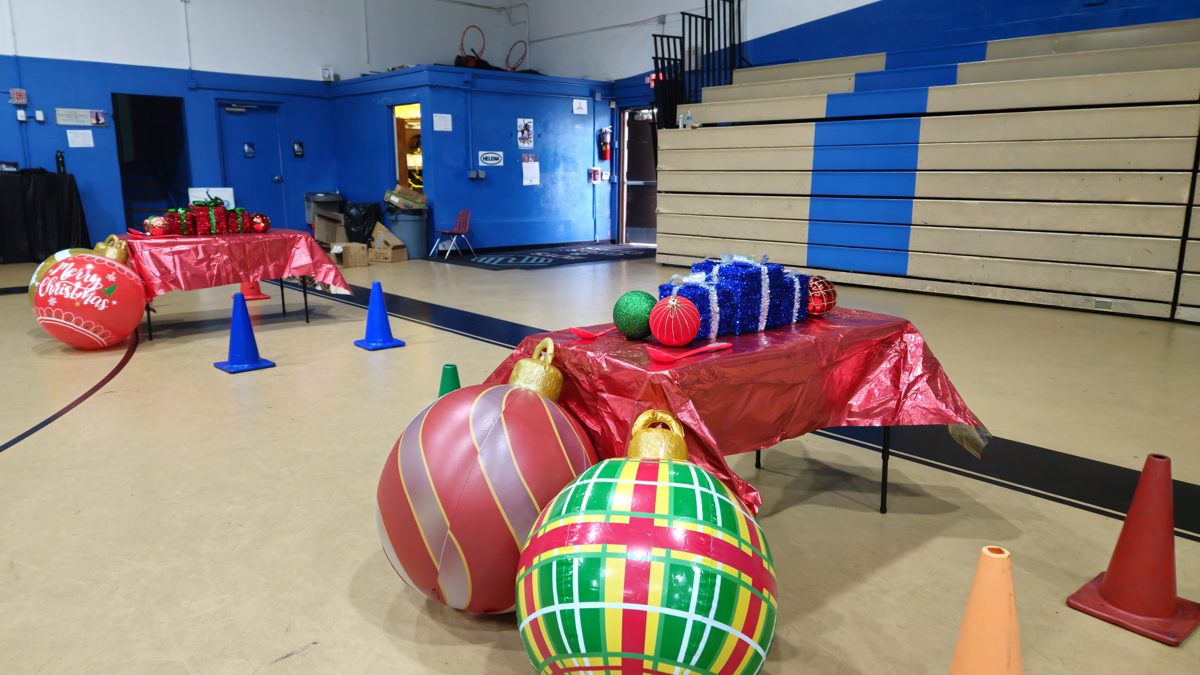 Giant Ornament and Spoon Race set up in a school gym with big Christmas ornaments, cones and a gift table