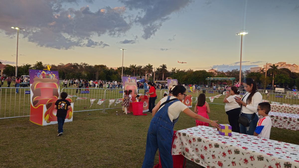 Families playing Crazy Games holiday games at a Christmas fair on a park field at sunset