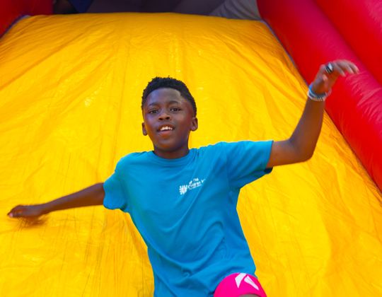 Kid having fun sliding down a yellow inflatable slide
