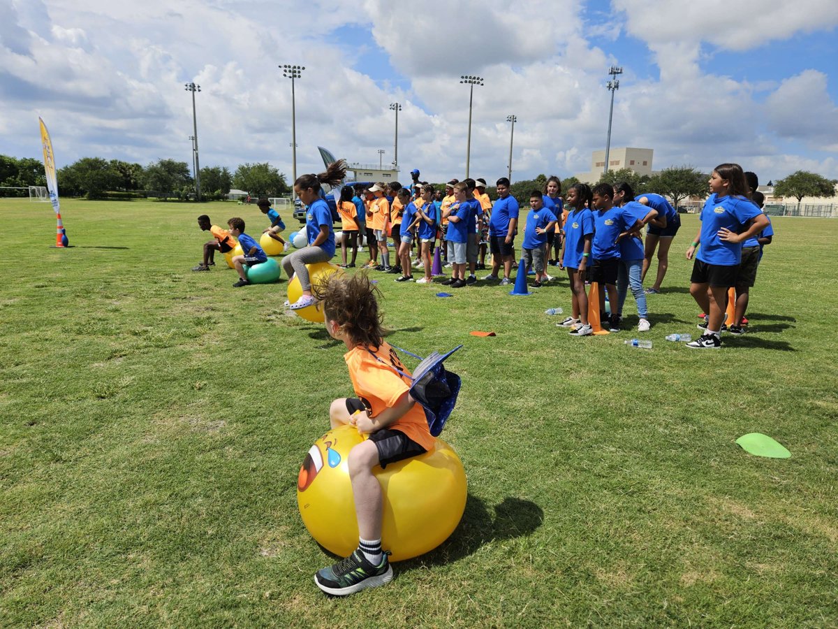Kids racing on yellow hopper balls on a park field