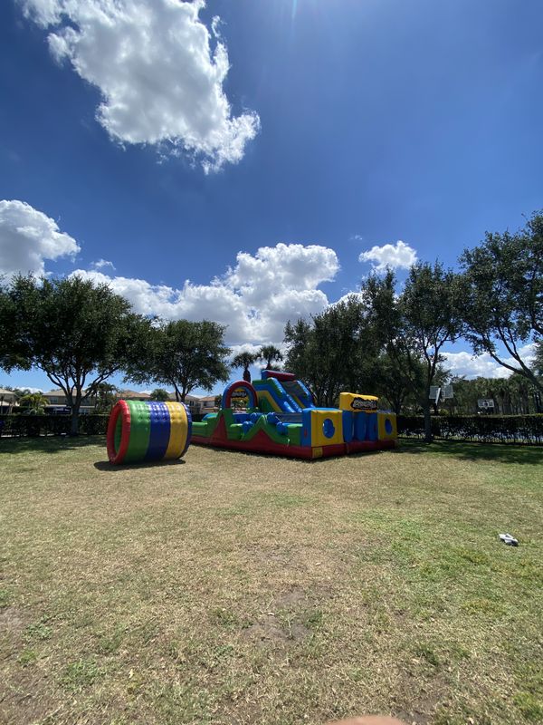 Inflatable obstacle course and crawl tunnel from Crazy Games FL set up on grass under a blue sky