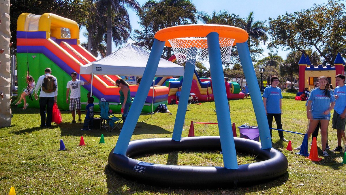 Giant inflatable Jumbo Basketball hoop set up on the grass at a sunny park party with kids and staff around it