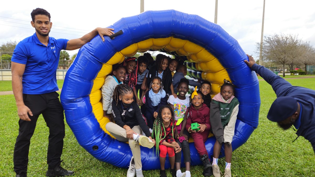 A big group of kids posing inside a giant inflatable hamster wheel at an outdoor park event