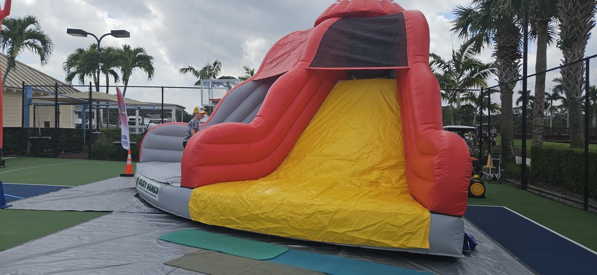 Crazy Games FL Lava Rock Slide set up on a court at a park event with palm trees in West Palm Beach