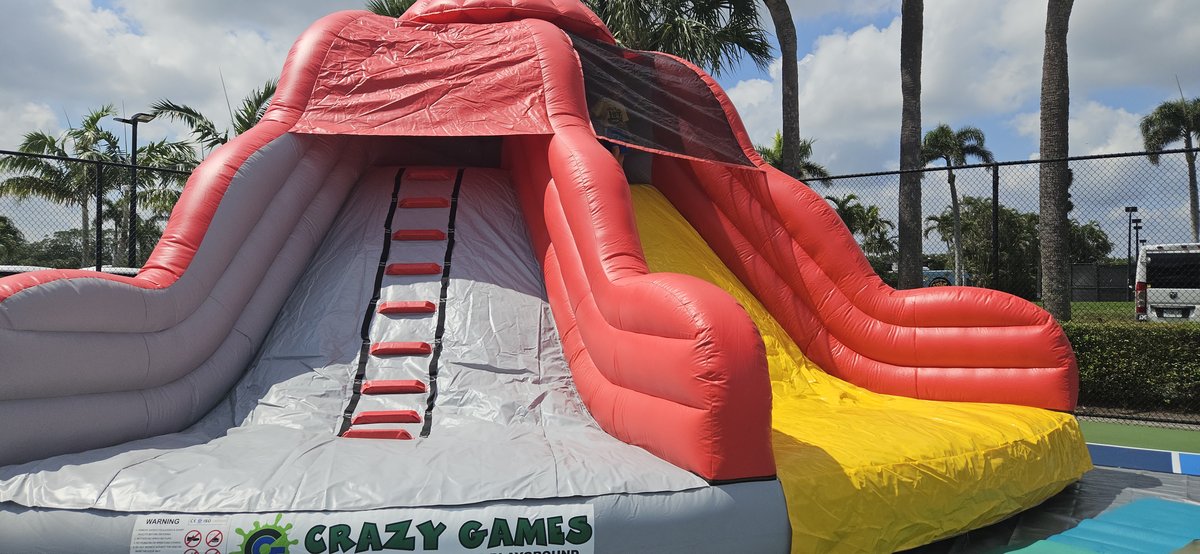 Crazy Games FL Lava Rock Slide set up on a hard sports court at an outdoor event in Palm Beach County