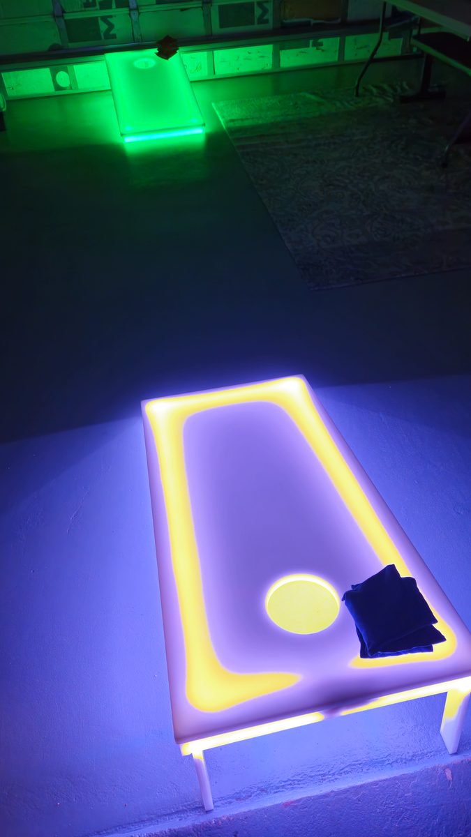 Glowing LED Lighted Cornhole board with bean bags at an evening party in Palm Beach County
