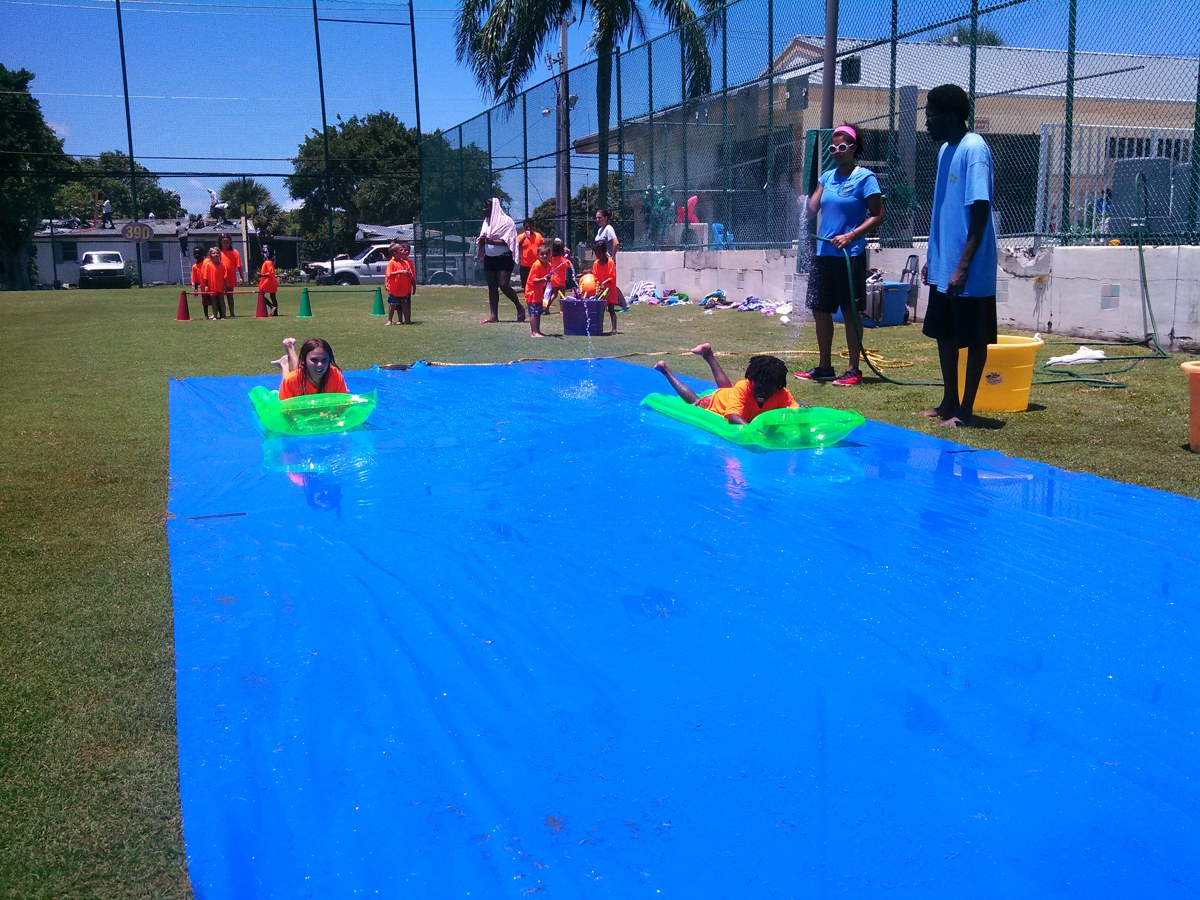 Long blue Crazy Games Slip N Slide set up on a school field in South Florida