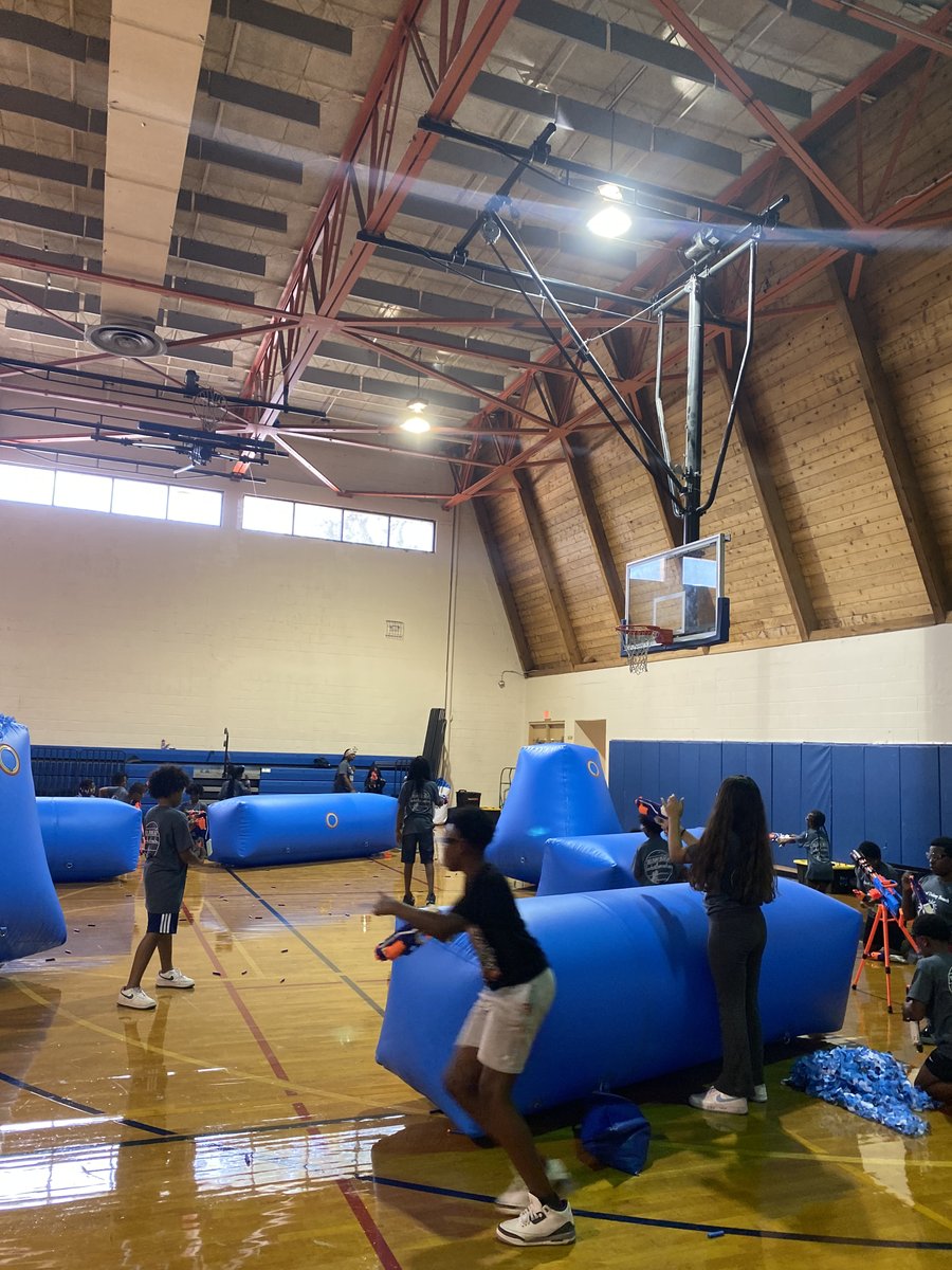 Kids playing Crazy Games FL Nerf Wars between blue inflatable bunkers in a school gym in Palm Beach County