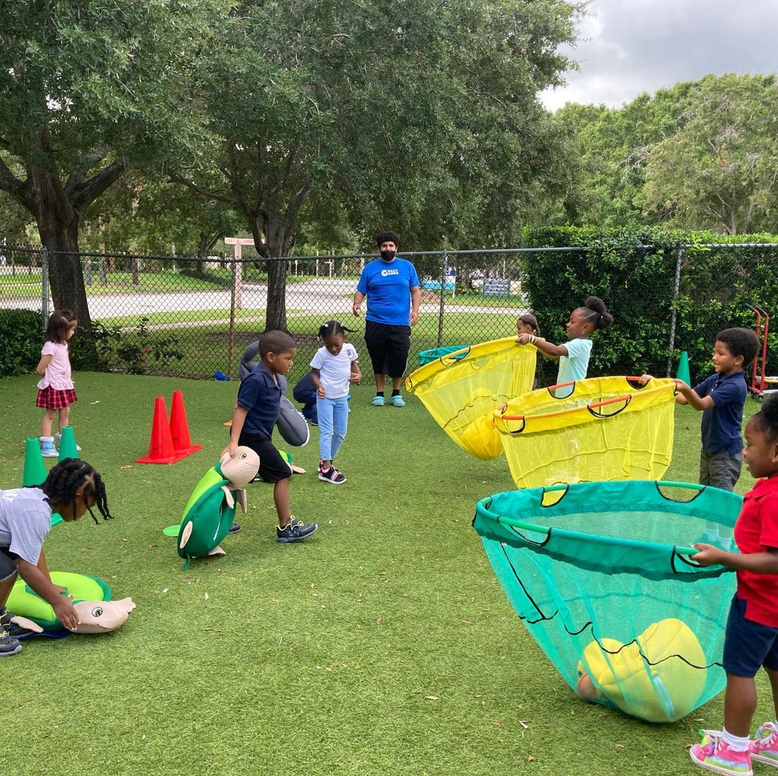 Kids playing a net catch relay field game on a grass field in South Florida