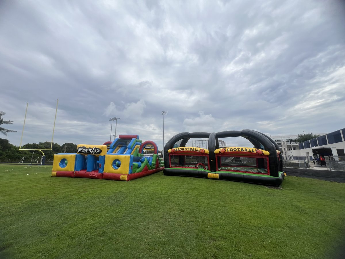 Inflatable obstacle course and the Crazy Games 4 Sports Arena set up on a school field under a cloudy sky in Palm Beach County