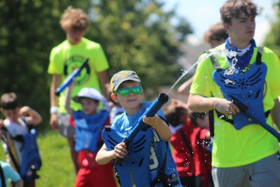 Kids running with water blasters in a Crazy Water Tag game