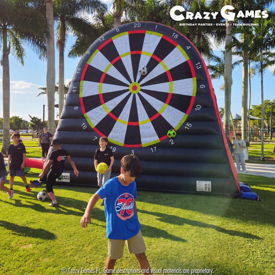Kids kicking balls at the giant soccer dartboard at a school