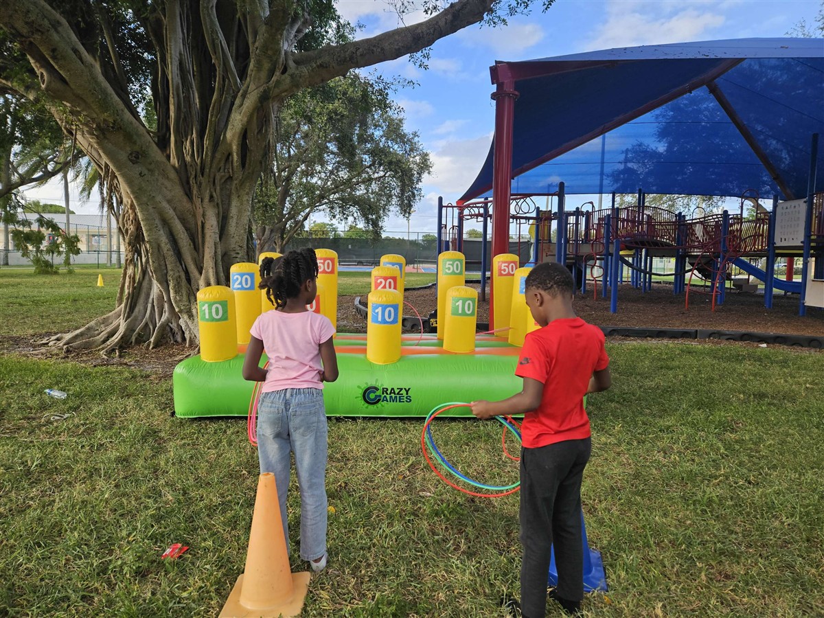 Two kids playing the Crazy Games Classic Ring Toss on a school lawn in Palm Beach County