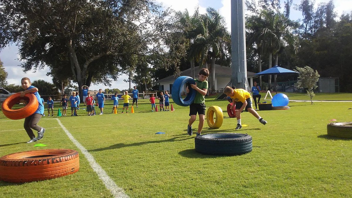 Kids running a colorful tire relay race at a community event on a park field