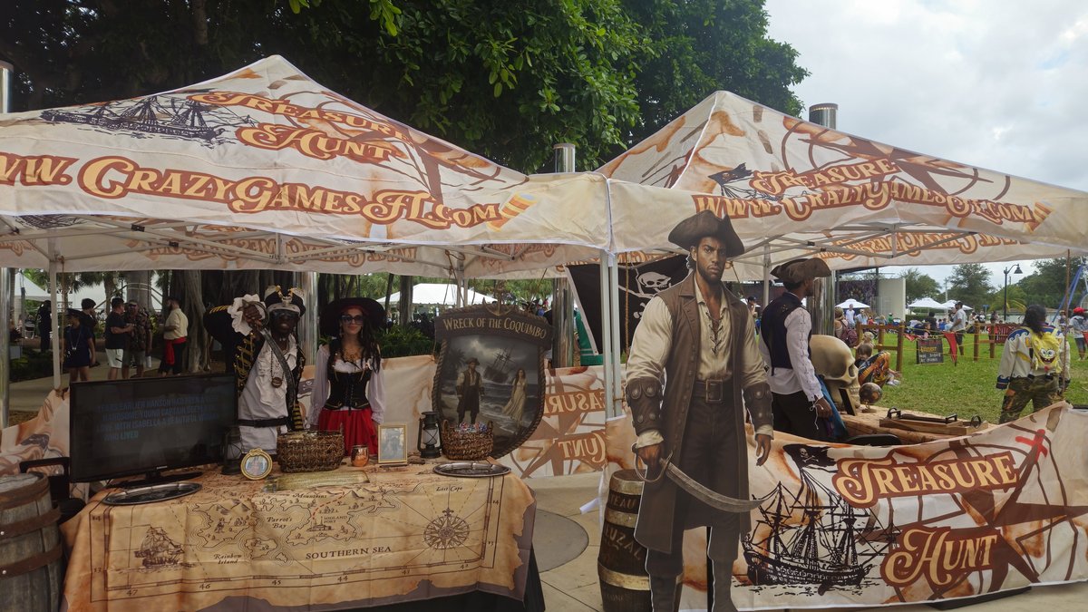 Crazy Games treasure hunt tents with pirate guides, a treasure map table and a pirate cutout at an outdoor community event